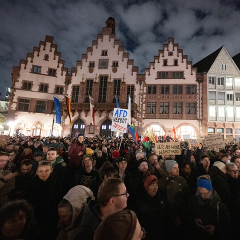 Im Hintergrund der Römer. das Frankfurter Rathaus, der Vordergrund ist mit Menschen gefüllt, die Plakate schwenken.