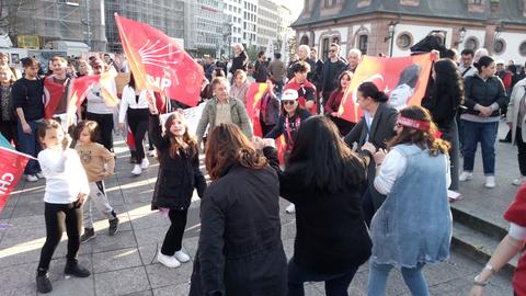 Demonstranten tanzen und schwenken Fahnen an der Frankfurter Hauptwache.