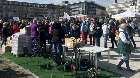 Demonstranten stehen auf Friedrichsplatz in Kassel.