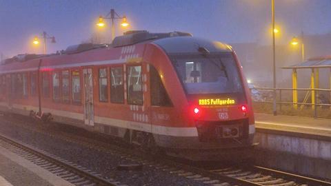 Ein roter Zug mit der Aufschrift "Puttgarden" steht am Morgen an einem Bahnsteig im Nebel