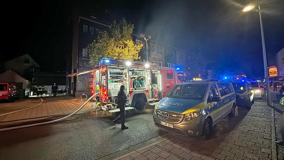 Polizisten, Polizeiwagen, Feuerwehrauto und Wasserschläuche vor einer Tiefgarageneinfahrt.