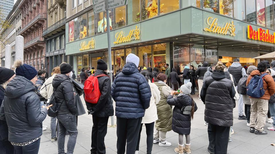 Menschen stehen in einer Schlange vor einem geschlossenen Schokoladenladen in Frankfurt