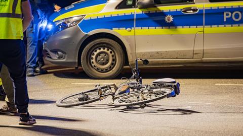 Ein E-Bike liegt auf der Straße vor einem Polizeiwagen.