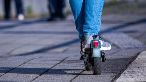 Ein Mann steht auf einem E-Scooter. 