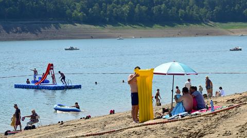 Ein Mann pumpt im Strandbad Waldeck am Edersee eine Luftmatratze auf.