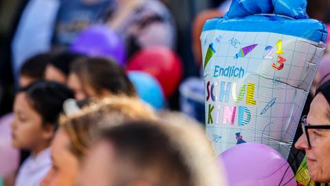 Ein Kind hält eine Schultüte mit der Aufschrift "Endlich Schulkind" in der Hand.