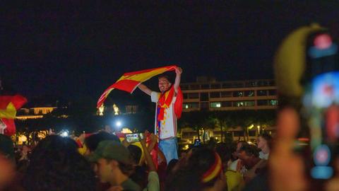 Ein Fußballfan hält die Spanienfahne hoch.