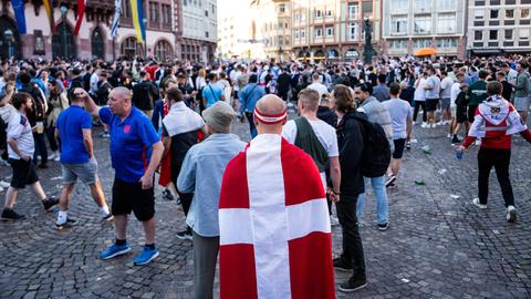 Ein Dänemark-Fan hat sich in eine Flagge des Landes gehüllt und schaut auf dem Römerberg in Frankfurt stehend zu England-Fans hinüber.