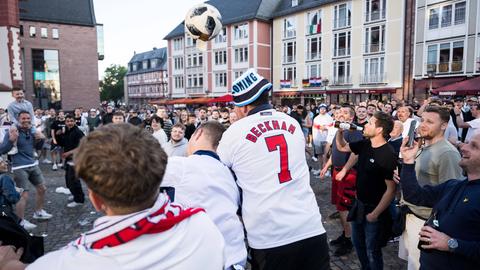 Männer unter anderem mit Beckham-Trikot und einem Fußball feiern auf dem Römerberg