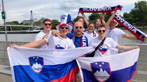 Fröhliche Menschen mit slowenischen Flaggen und Schals