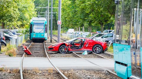 Beschädigter Ferrari steht auf Straßenbahn-Gleisen. Im Hintergrund eine Tram.