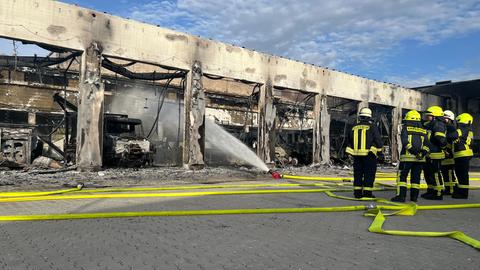 Feuerwehrleute stehen vor dem ausgebrannten Gerätehaus in Stadtallendorf