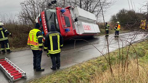 Ein Feuerwehrwagen liegt seitlich in einem Graben. 