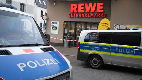 Polizeikräfte stehen nach einem Überfall auf einen Getränkemarkt vor dem Geschäft.