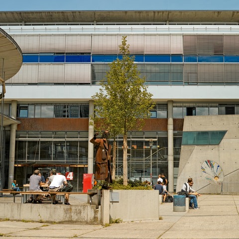 Studenten sitzen vor Gebäuden der Frankfurter Fachhochschule