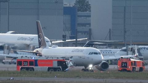 Nachdem das Flugzeug unplanmäßig zum Flughafen zurückkehren musste, stehen Feuerwehrfahrzeuge an dem gelandeten Airbus der Lufthansa.