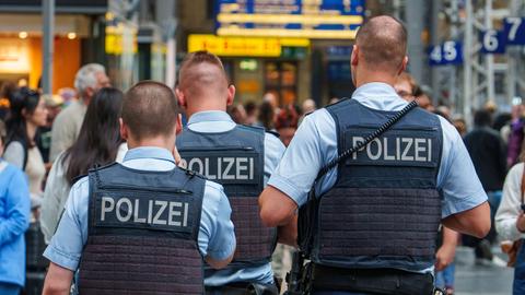 Polizisten patrouillieren in einem Bahnhofsgebäude.