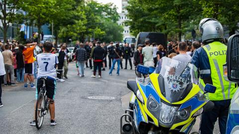 Erwachsene und Kinder in Trikots haben sich gesammelt, Polizist auf Motorrad.