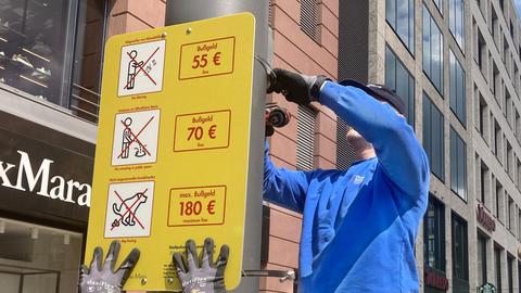 Monteure hängen in der Frankfurter Innenstadt ein Schild für mehr Sauberkeit auf.