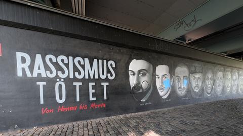 Graffito mit den teils beschmierten Gesichtern der Hanau-Opfer unter der Frankfurter Friedensbrücke