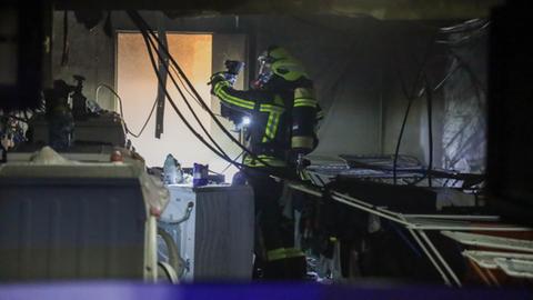 Ein Feuerwehrmann steht im Keller eines Hauses an einer Waschmaschine