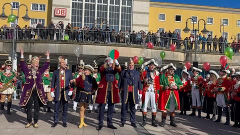 Fastnachter lassen rote, grüne und weiße Ballons fliegen