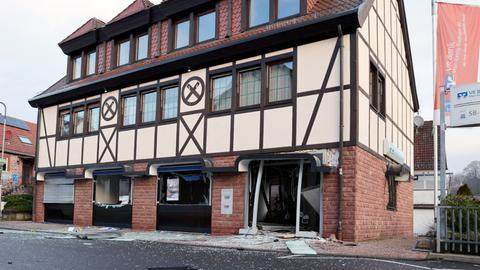 Gebäude von außen mit einem zerstörten Eingang im Erdgeschoss. Daneben Fahnen mit dem Volksbank-Logo.