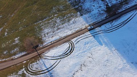 Luftaufnahme von Straße, die durch eine leicht verschneite Landschaft führt