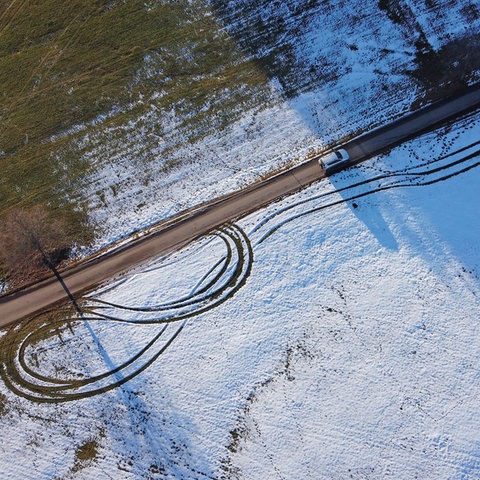 Luftaufnahme von Straße, die durch eine leicht verschneite Landschaft führt