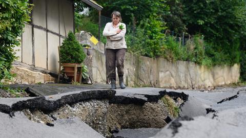 Anwohnerin Christina Wiesmann-Günter steht neben einer nach einem Unwetter zerstörten Fahrbahn im Gottsbürener Stadtteil Trendelburg.