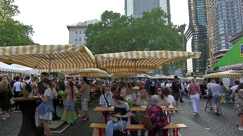 Menschen sitzen unter Schirmen auf Bierbänken