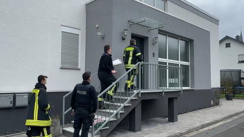 Mehrere Feuerwehrleute betreten ein Haus