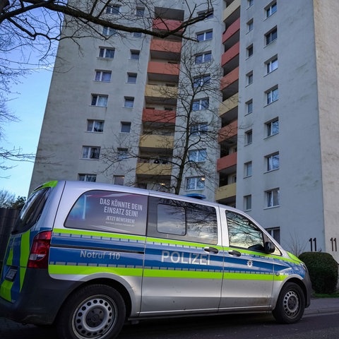 Ein Polizeiauto parkt vor einem Hochhaus. 