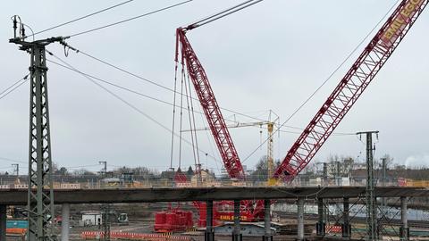 Ein großer roter Kran steht an der Baustelle an der Brücke am Hauptbahnhof.