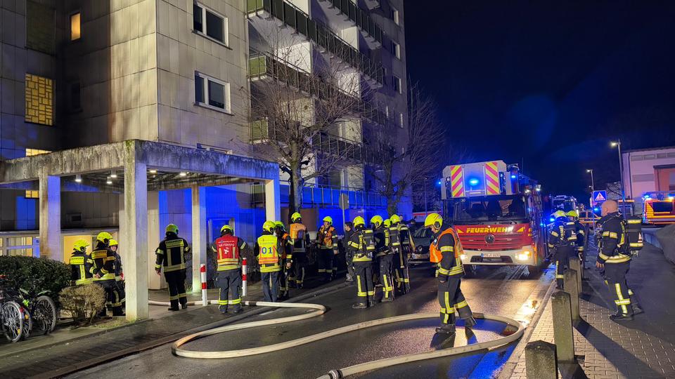 Feuerwehrfahrzeug und Feuerwehrleute auf der Straße vor dem Eingang zu einem Haus