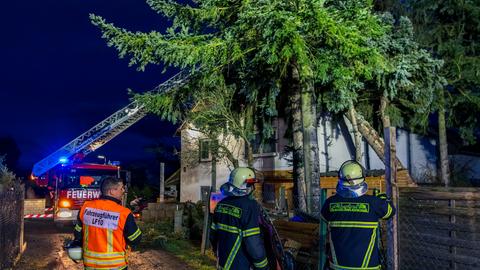 Feuerwehrleute bei dem Einsatz in Weiterstadt: Ein großer Baum liegt auf dem Dach eines Wohnhauses. 