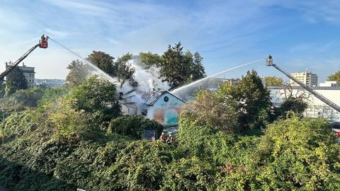 Feuerwehrleute sprühen Wasser auf ein brennendes Haus