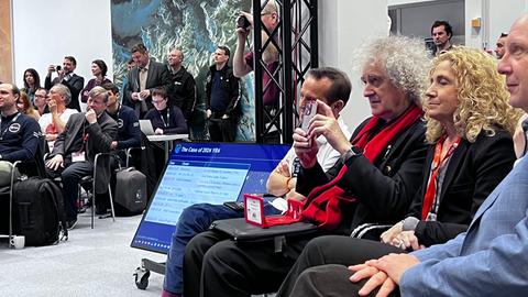 Brian May auf einem Stuhl in der ersten Reihe während der Präsentation 