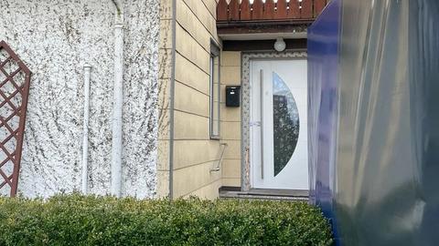 Wohnhaus mit Eingangstür, an der ein Polizei-Siegel hängt.