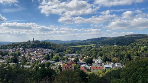 Weitblick über Bäume und Häuser bis zu einer Burg auf einem Berg