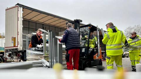 Vier Männer beim Beladen eines Lkws mit einem Gabelstapler.