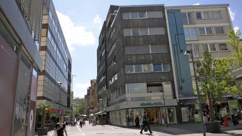 Eine Straße in der Fußgängerzone, rechts hohe Gebäude.