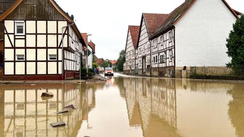 Eine mit braunem Wasser überflutete Straße zwischen Fachwerkhäusern.