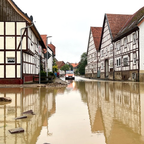 Eine mit braunem Wasser überflutete Straße zwischen Fachwerkhäusern.