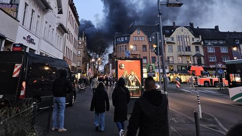 Menschen stehen auf Straße und gucken zu einer Rauchsäule über der Höchster Innenstadt