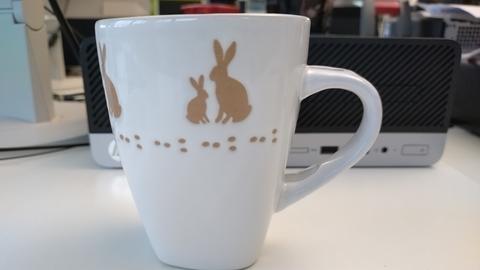 Weiße Kaffeetasse mit kleinen und großen braunen Hasen