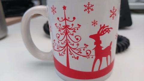 Weiße Tasse mit roten Hirsch und geschmücktem Tannenbaum