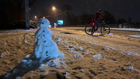 ein schneemann, daneben einRadfahrer