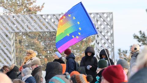 Eine Regenbogenflagge ragt aus der Menschenmenge.