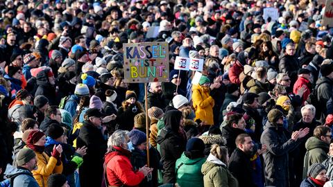 "Kassel ist bunt" - das Schild ragt aus der Menschenmenge.